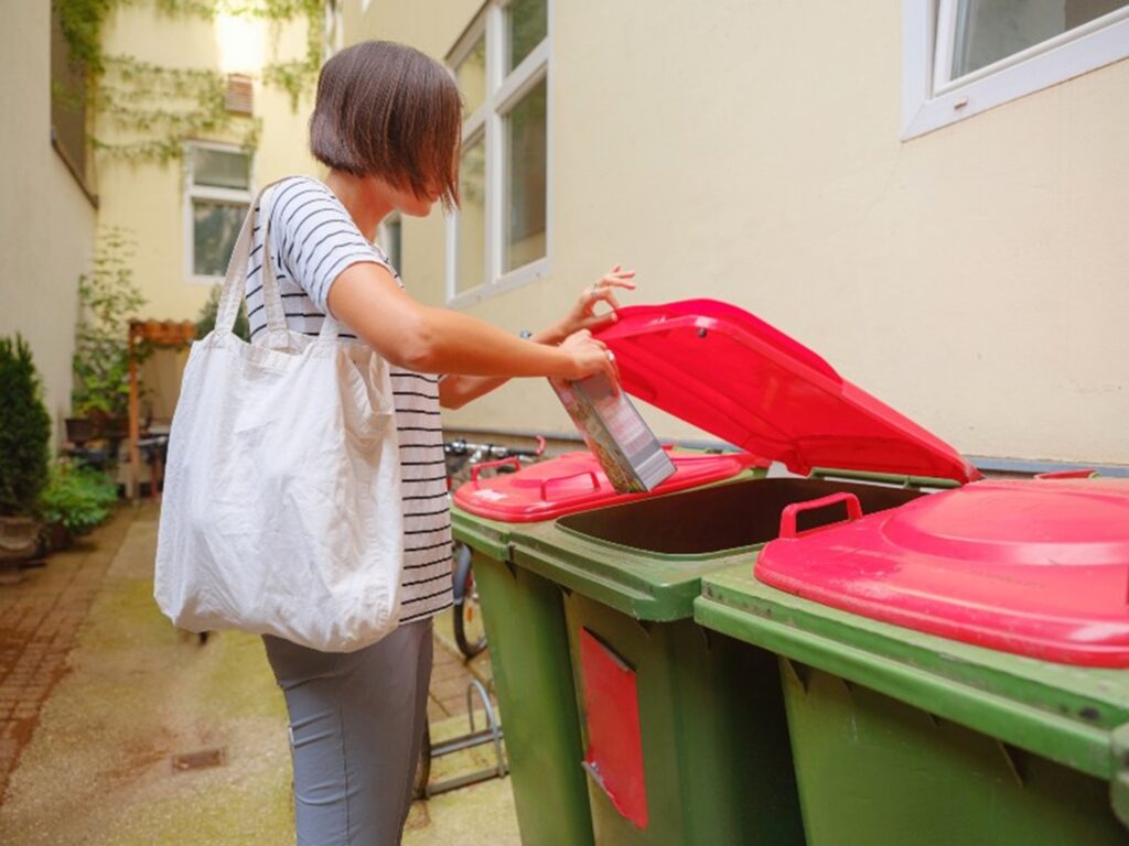 Woman throwing garbage in bins by Okon Recycling